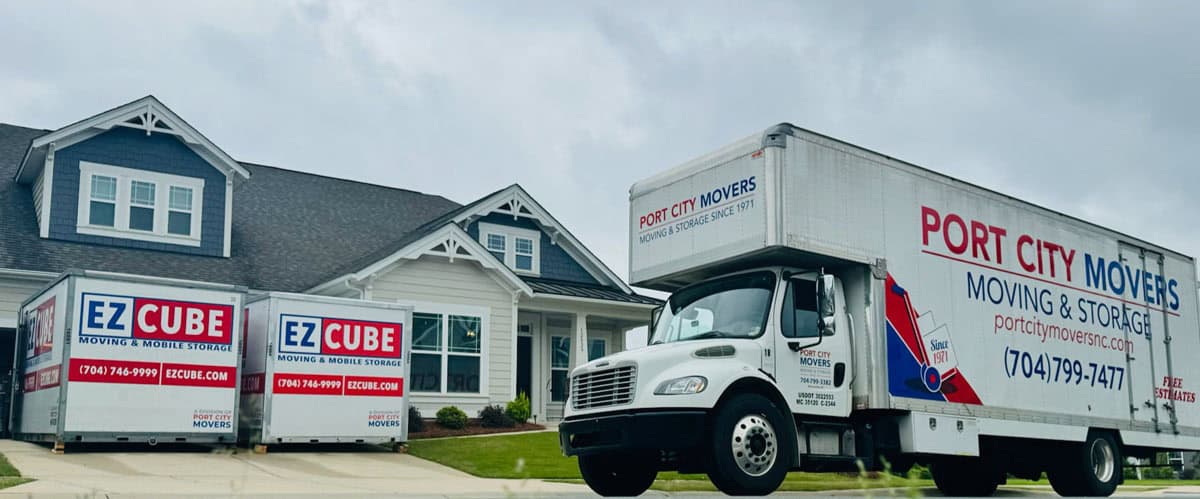 Port City Movers truck and two EZCube mobile storage containers parked in front of a suburban home on a cloudy day.